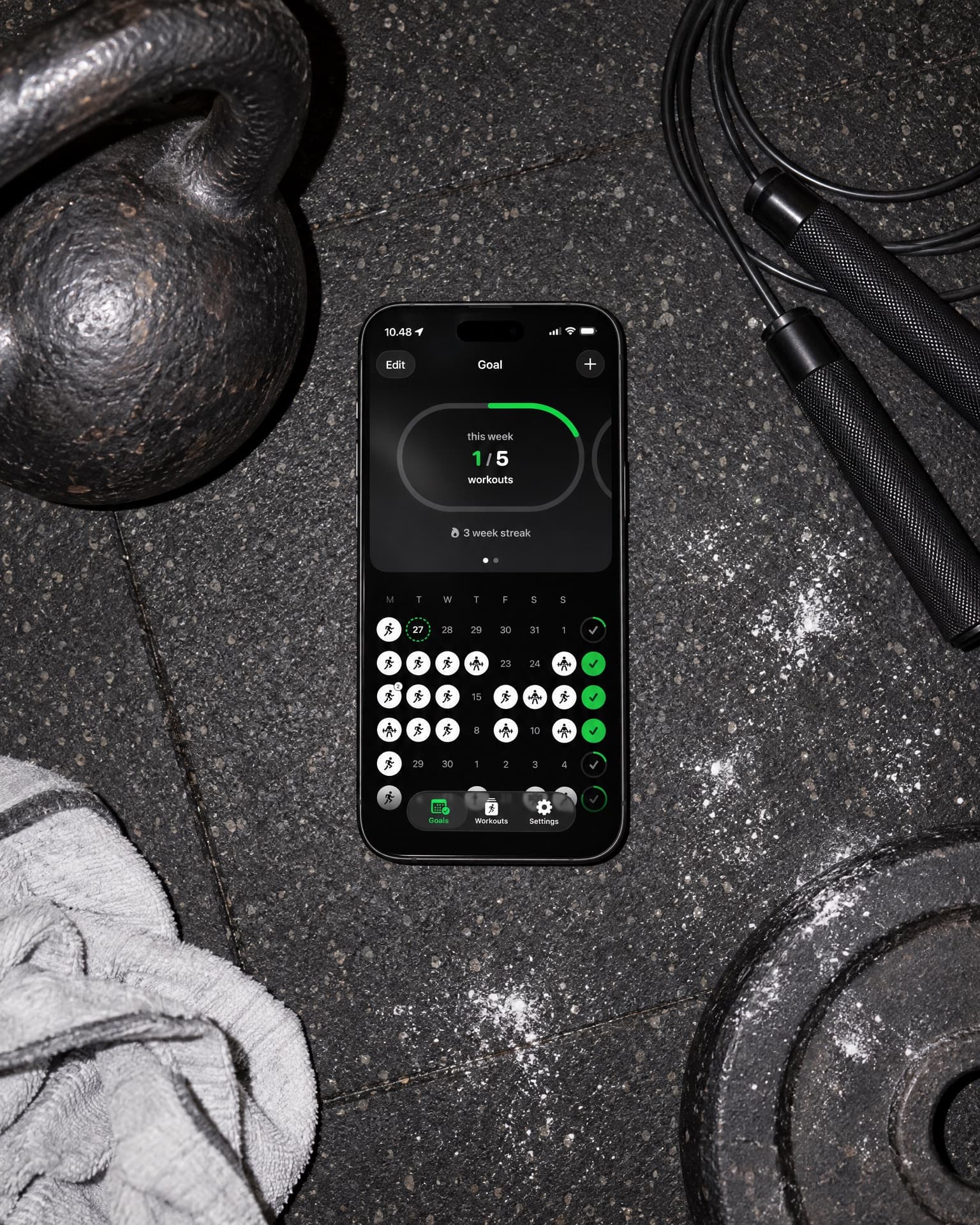 SweatCount on an iPhone, lying on a gym floor between a kettlebell, a jump rope and a towel